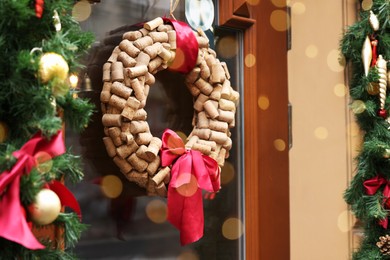 Photo of Beautiful Christmas wreath made of wine corks hanging on glass door