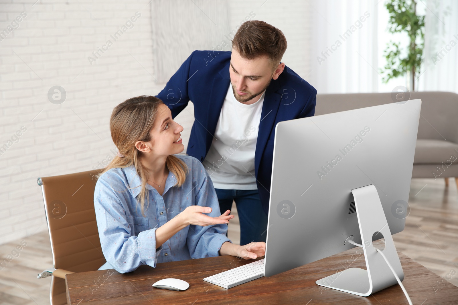 Photo of Man helping his colleague work with computer in office