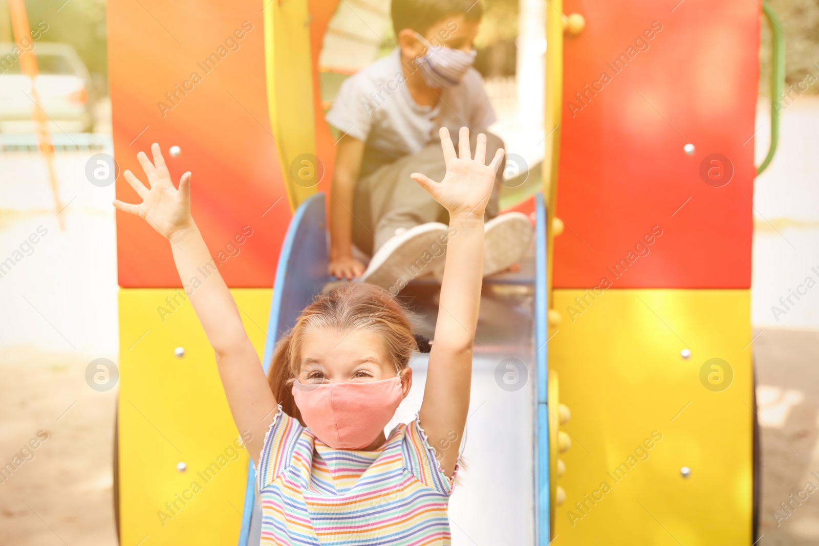 Photo of Little children with medical face masks on playground during covid-19 quarantine