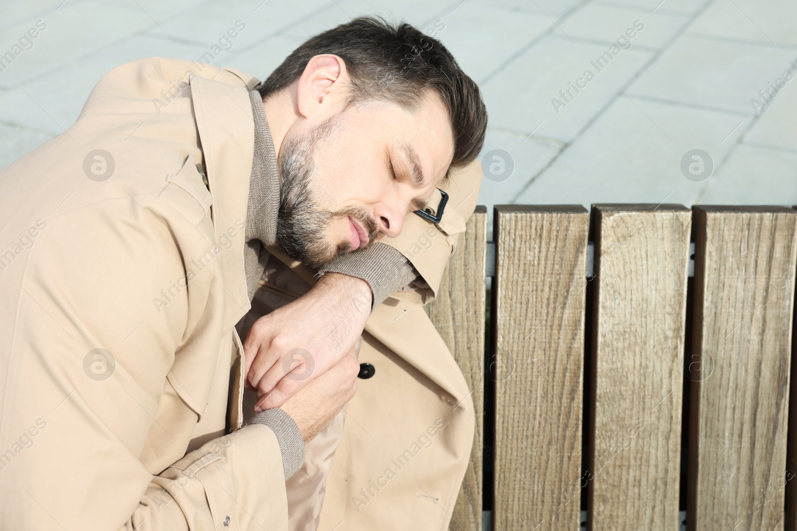 Photo of Tired man sleeping on bench outdoors. Space for text