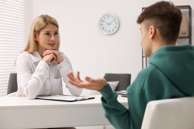 Photo of Psychologist working with teenage boy at table in office