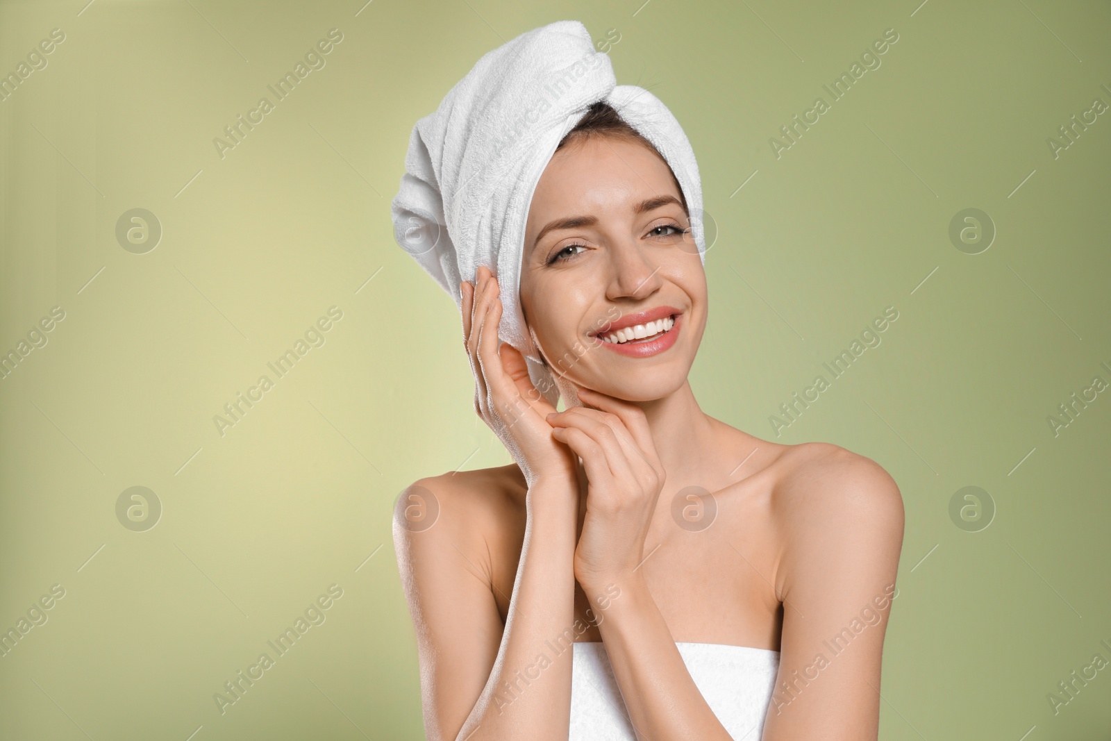 Photo of Beautiful young woman with hair wrapped in towel after washing on light green background