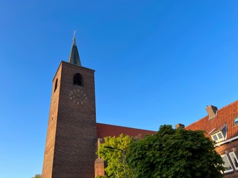 Beautiful old tower and house against blue sky, low angle view