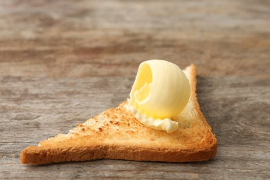 Photo of Toasted bread with fresh butter curl on wooden table