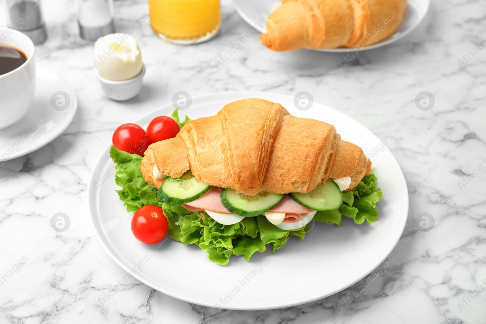 Photo of Tasty croissant sandwich with sausage on table