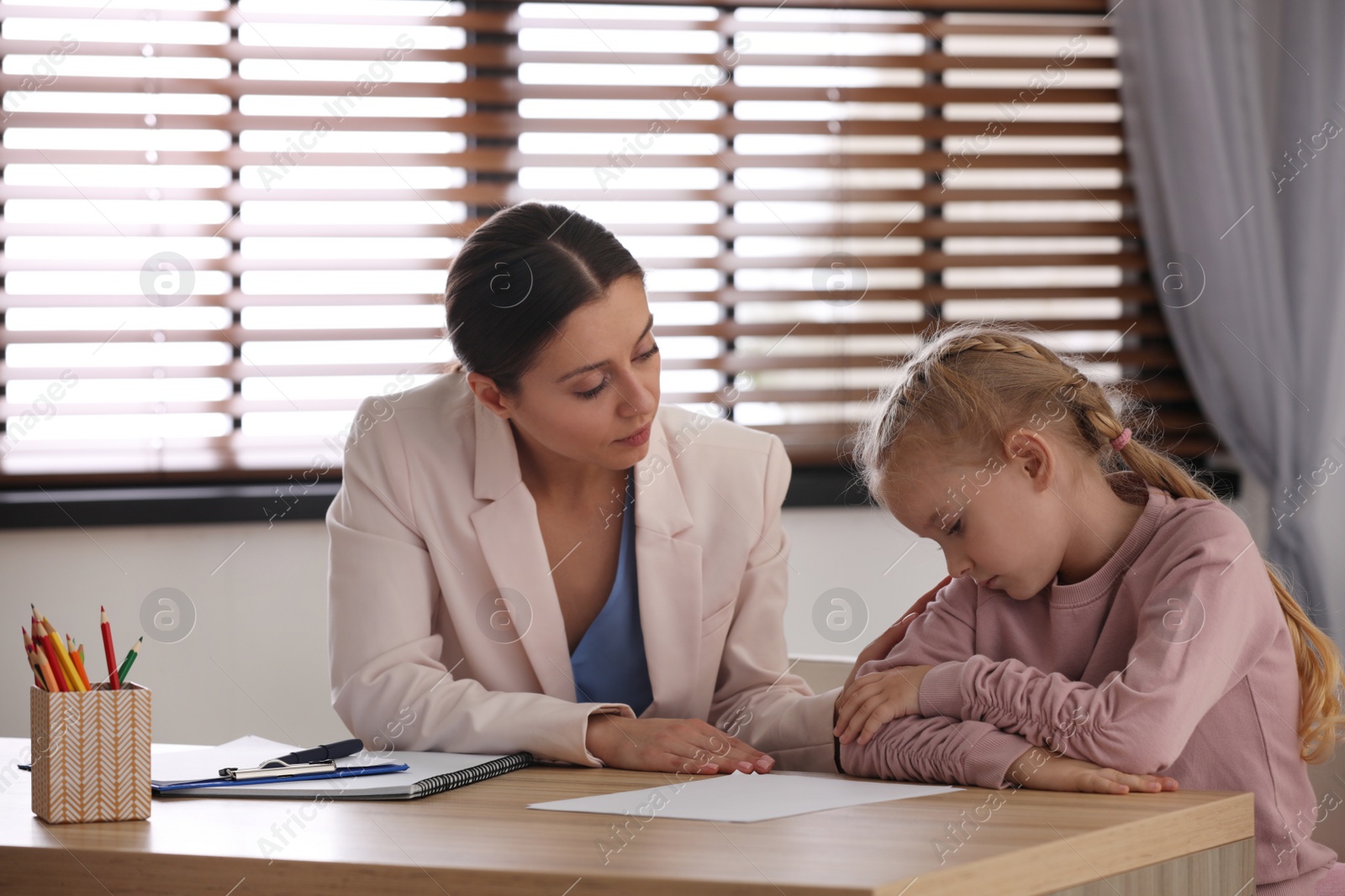 Photo of Child psychotherapist working with little girl in office