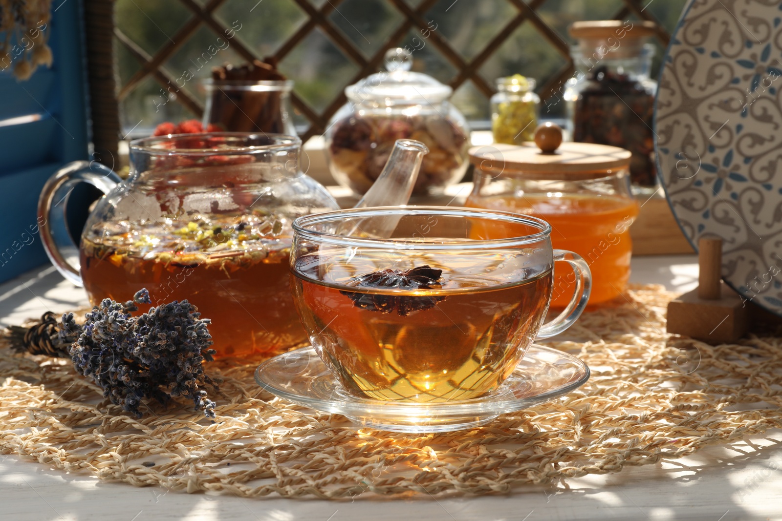 Photo of Aromatic tea with different dry plants and honey on white table