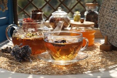 Aromatic tea with different dry plants and honey on white table