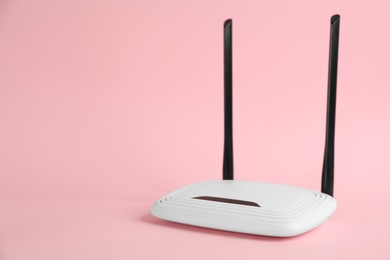 Modern Wi-Fi router on light pink background. Space for text