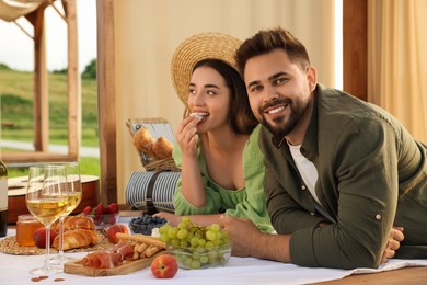 Photo of Romantic date. Beautiful couple having picnic in wooden gazebo