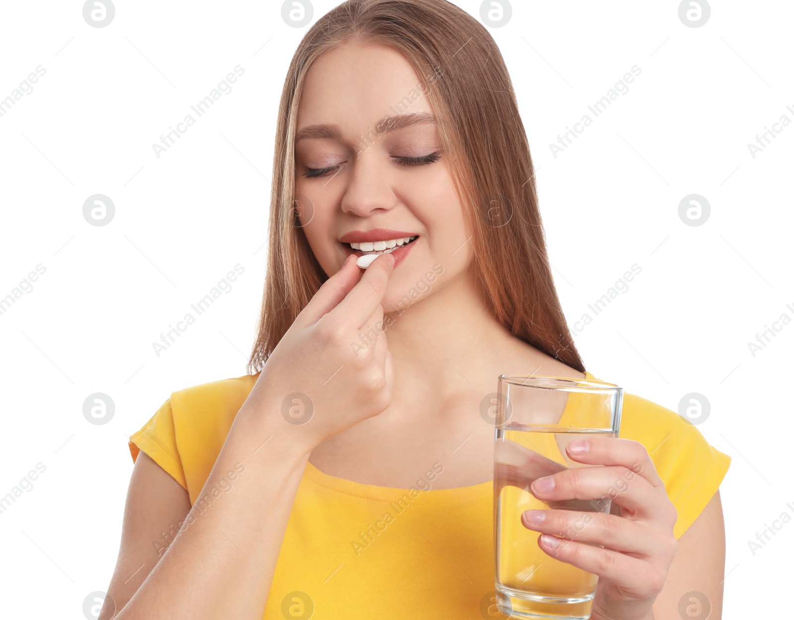 Photo of Young woman with glass of water taking vitamin pill on white background