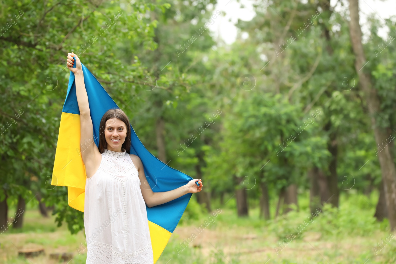 Photo of Young woman with flag of Ukraine outdoors