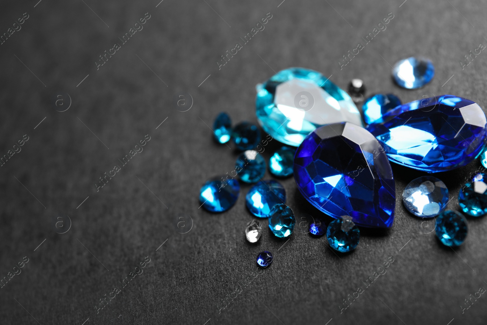 Photo of Pile of different beautiful gemstones on black background. Space for text