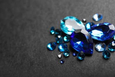 Pile of different beautiful gemstones on black background. Space for text