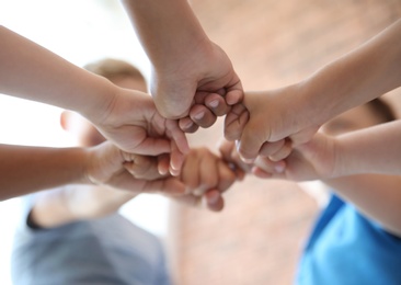 Photo of Little children putting their hands together on blurred background. Unity concept