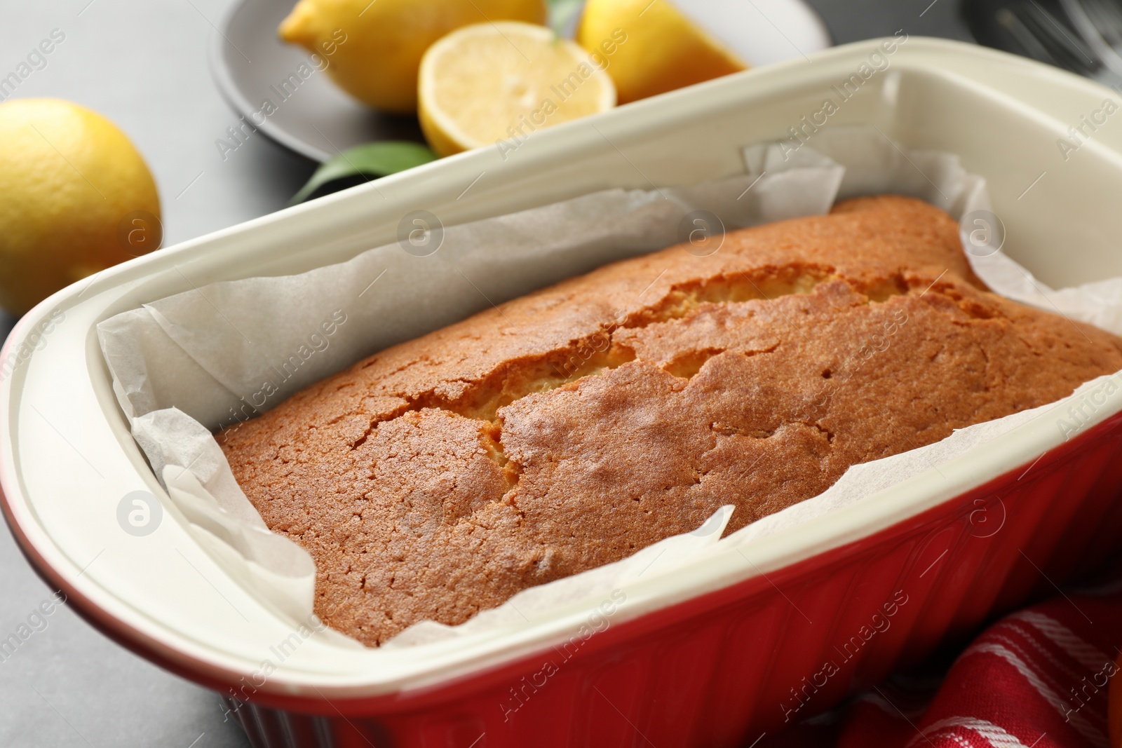 Photo of Tasty lemon cake in baking dish on table, closeup