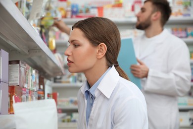 Photo of Professional pharmacist near shelves in modern drugstore