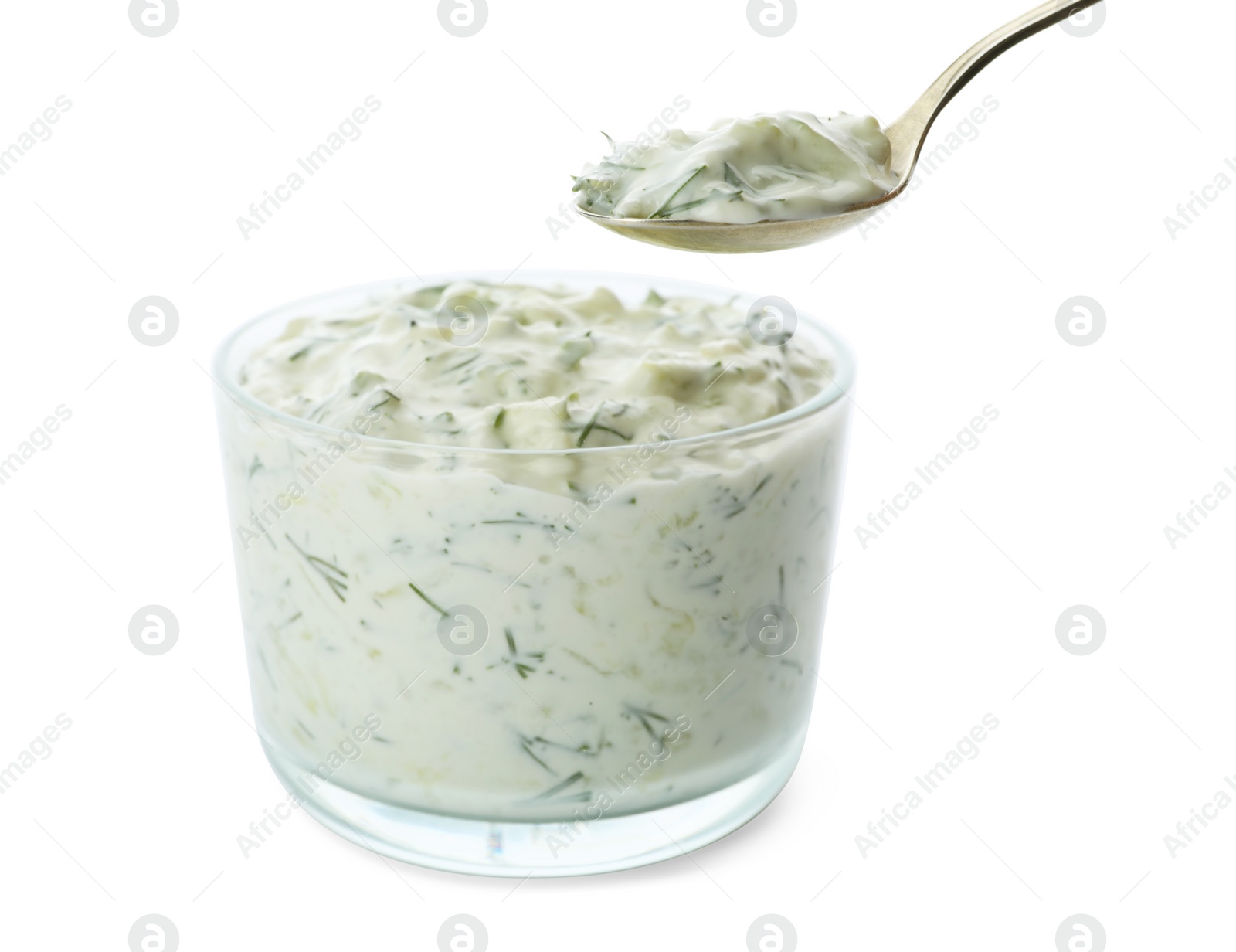 Photo of Spoon and bowl of cucumber sauce on white background. Traditional Tzatziki