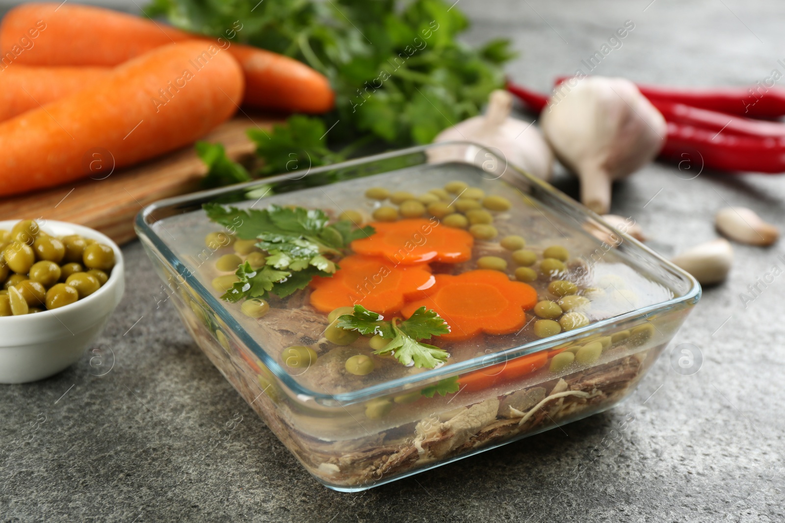 Photo of Delicious aspic with meat and vegetables served on grey table, closeup