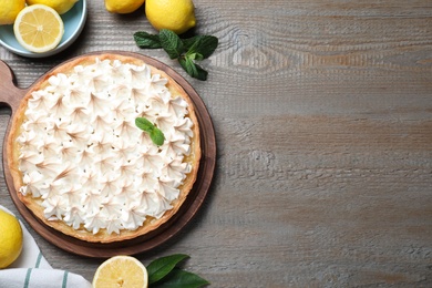 Photo of Flat lay composition with delicious lemon meringue pie on wooden table, space for text