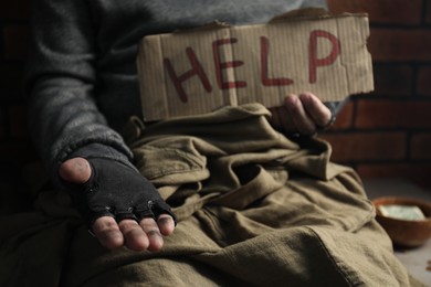 Poor homeless man with help sign begging for money, closeup. Charity and donation