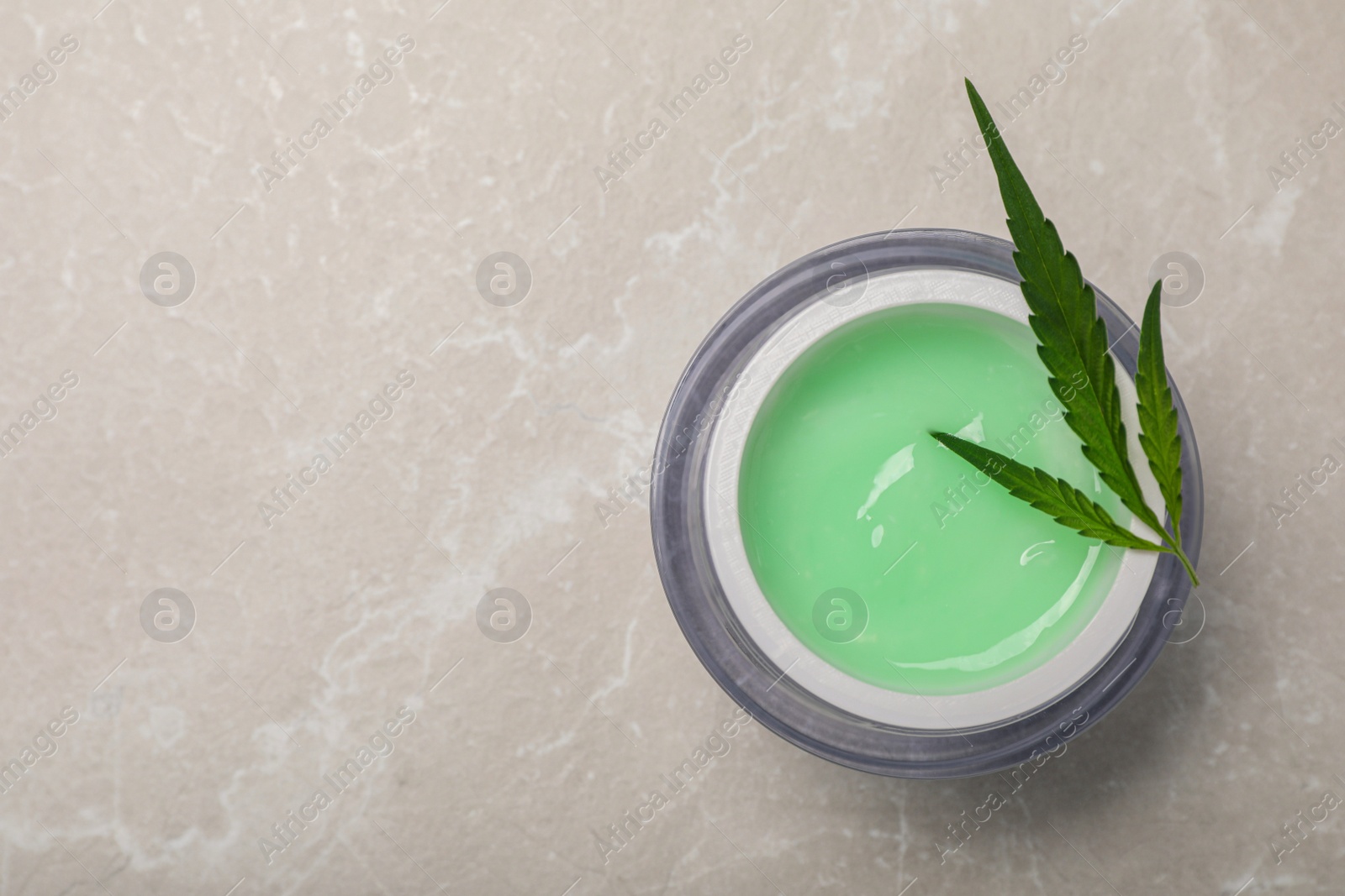 Photo of Jar of hemp cream and leaf on light table, top view with space for text. Natural cosmetics