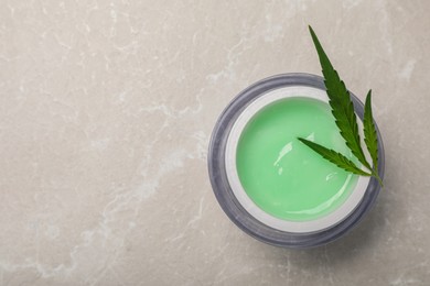 Photo of Jar of hemp cream and leaf on light table, top view with space for text. Natural cosmetics