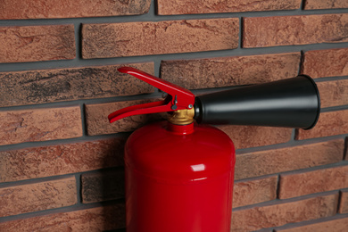 Photo of Fire extinguisher near brick wall, closeup view