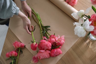 Florist making beautiful peony bouquet at table, top view