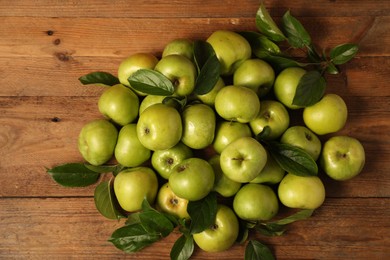 Photo of Ripe green apples with leaves on wooden table, flat lay