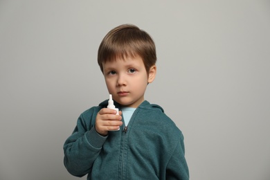 Photo of Little boy with nasal spray on light grey background