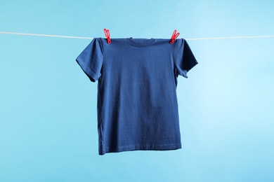One t-shirt drying on washing line against light blue background
