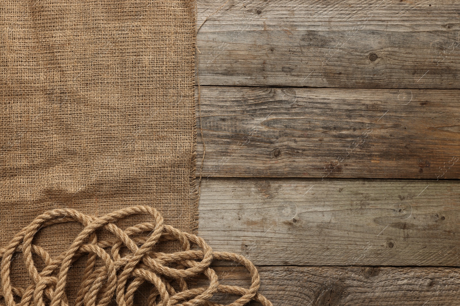 Photo of Burlap fabric and jute on wooden table, top view. Space for text