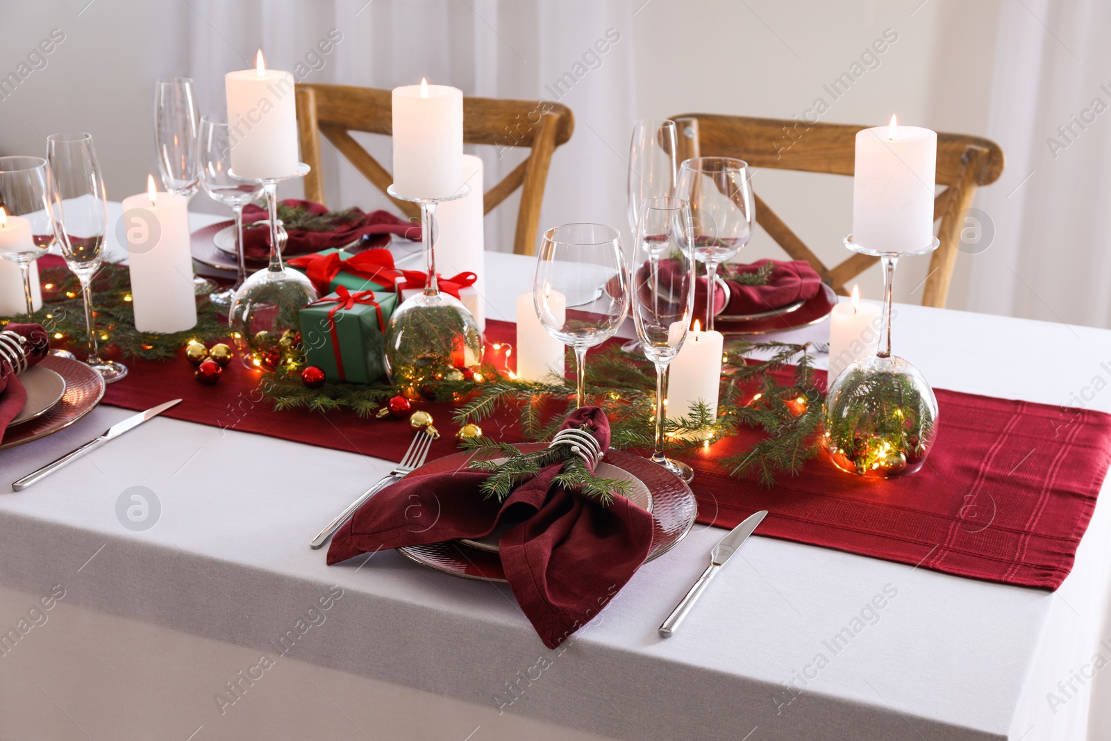 Photo of Christmas table setting with burning candles and festive decor