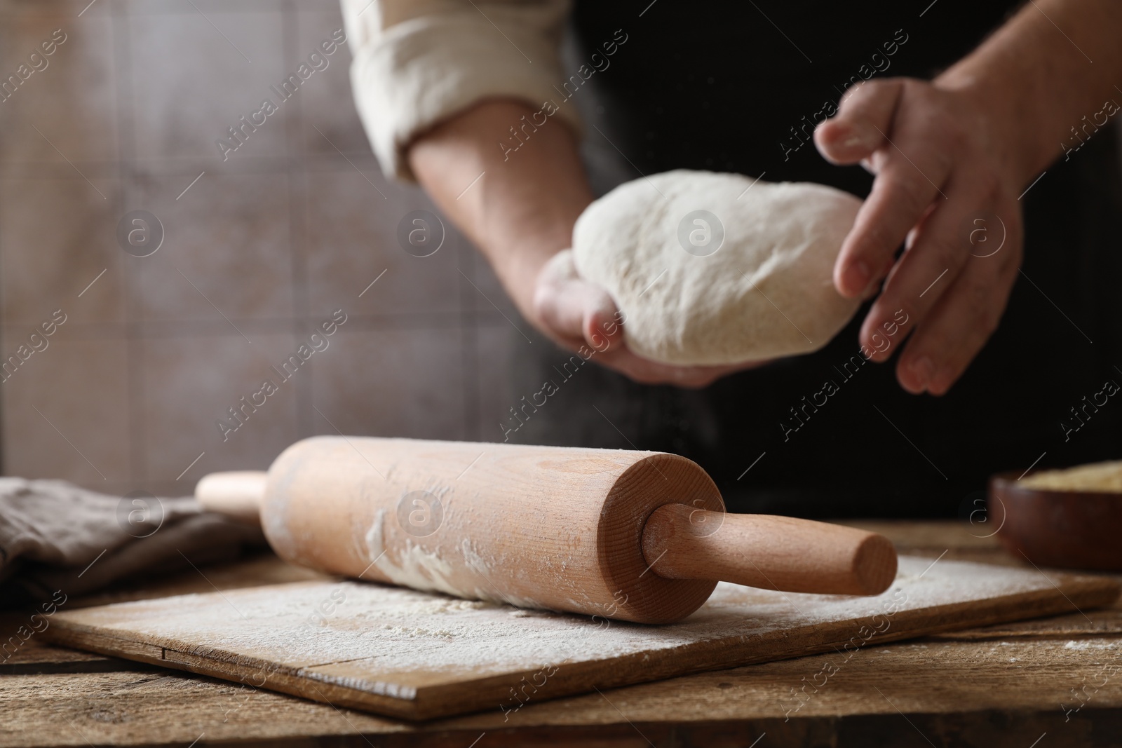 Photo of Man making dough at wooden table, closeup