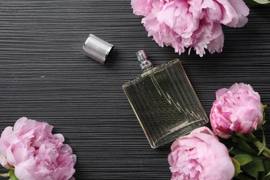 Luxury perfume and floral decor on dark background, flat lay