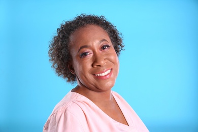 Portrait of happy African-American woman on light blue background