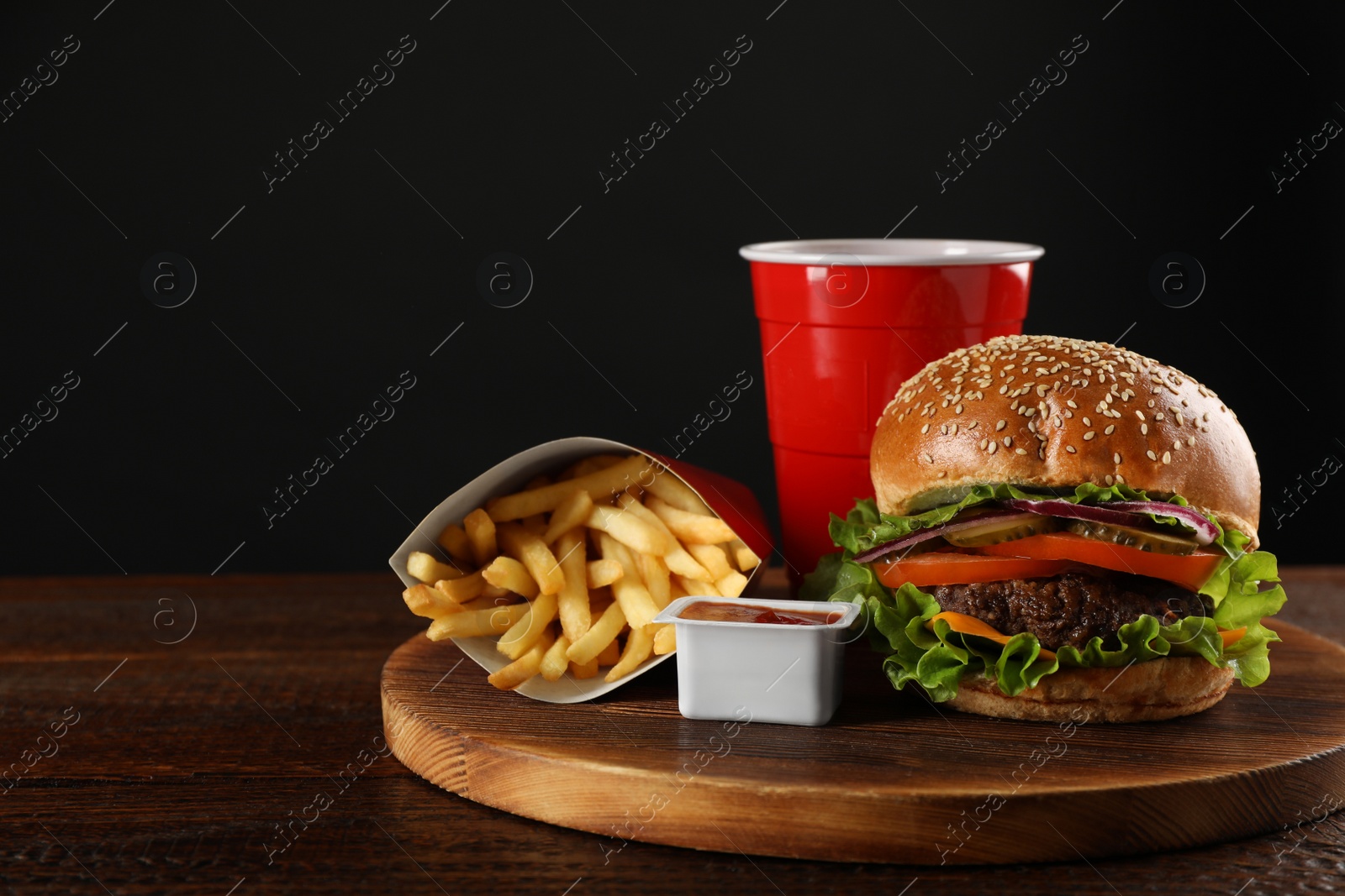 Photo of Burger, French fries, ketchup and refreshing drink on wooden table, space for text. Fast food