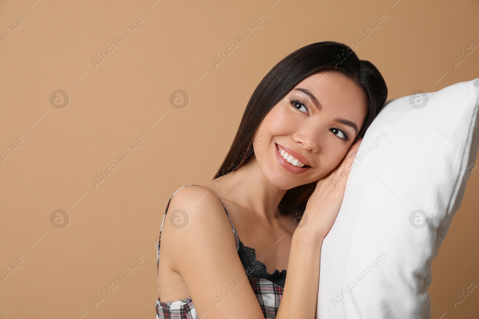 Photo of Beautiful Asian woman with pillow on beige background. Bedtime