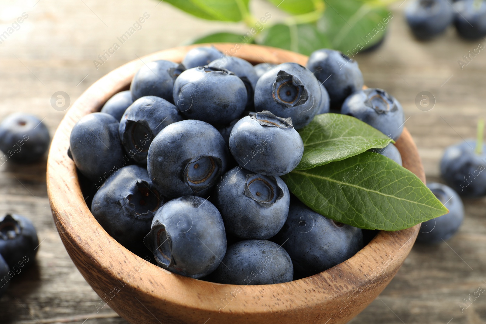 Photo of Bowl of fresh tasty blueberries on table, closeup