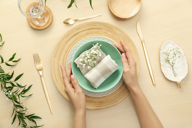 Woman setting table with flowers for festive dinner, top view