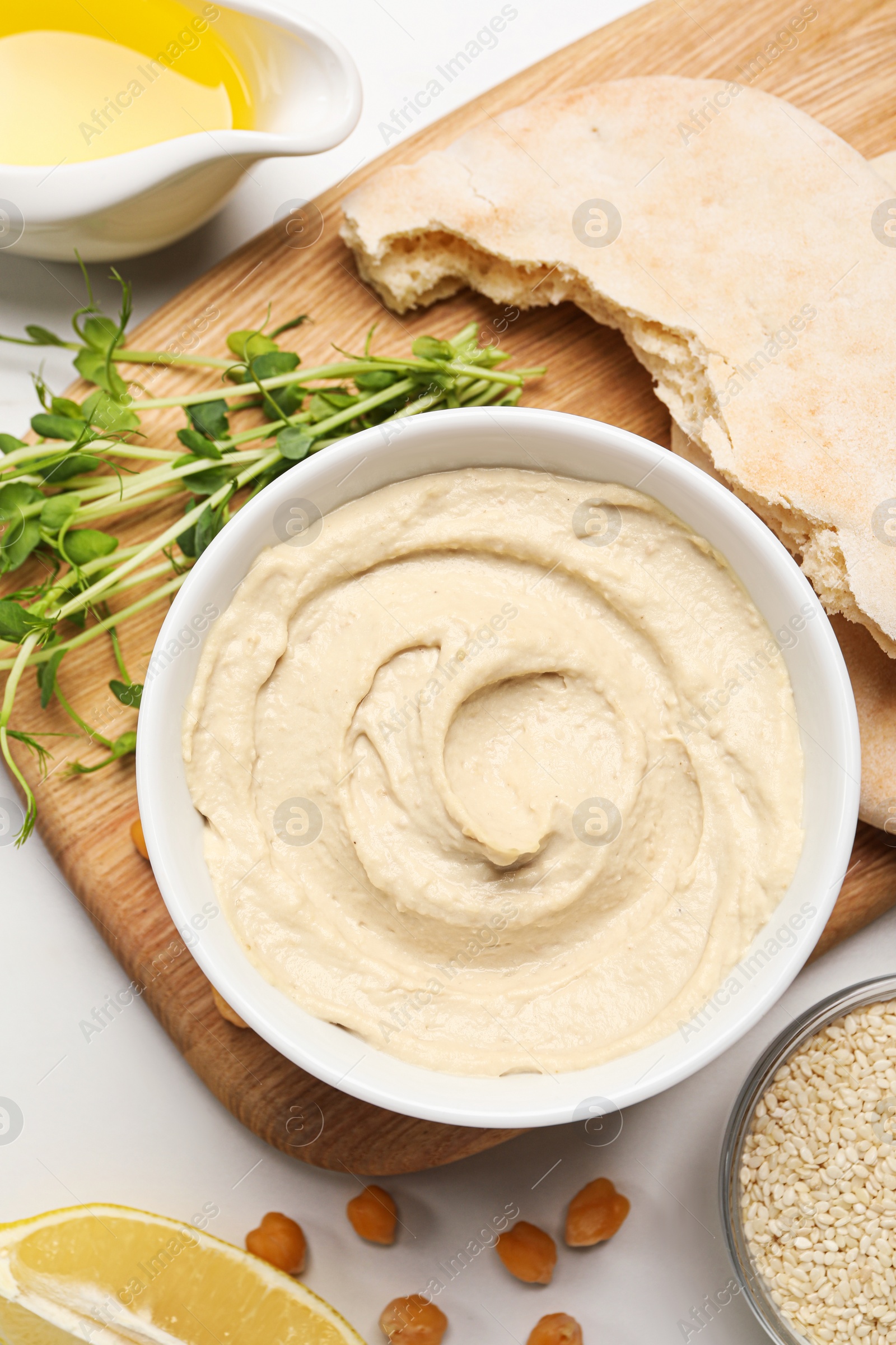 Photo of Delicious hummus and different ingredients on white table, flat lay