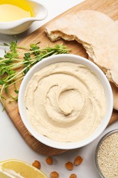 Delicious hummus and different ingredients on white table, flat lay