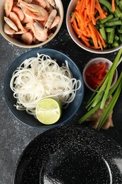 Photo of Flat lay composition with black wok and products on dark textured table