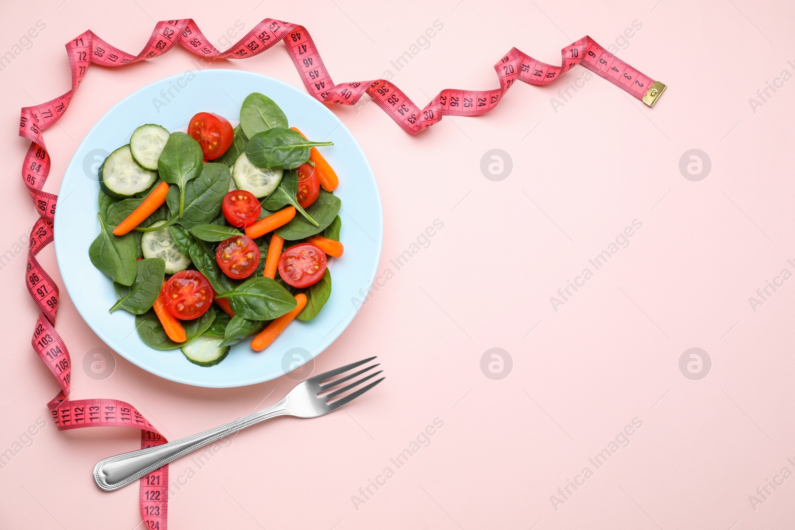 Photo of Measuring tape, fork and salad on pink background, flat lay. Space for text