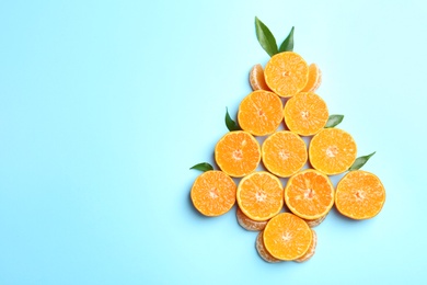 Christmas tree shape made with juicy tangerine on color background, top view. Space for text