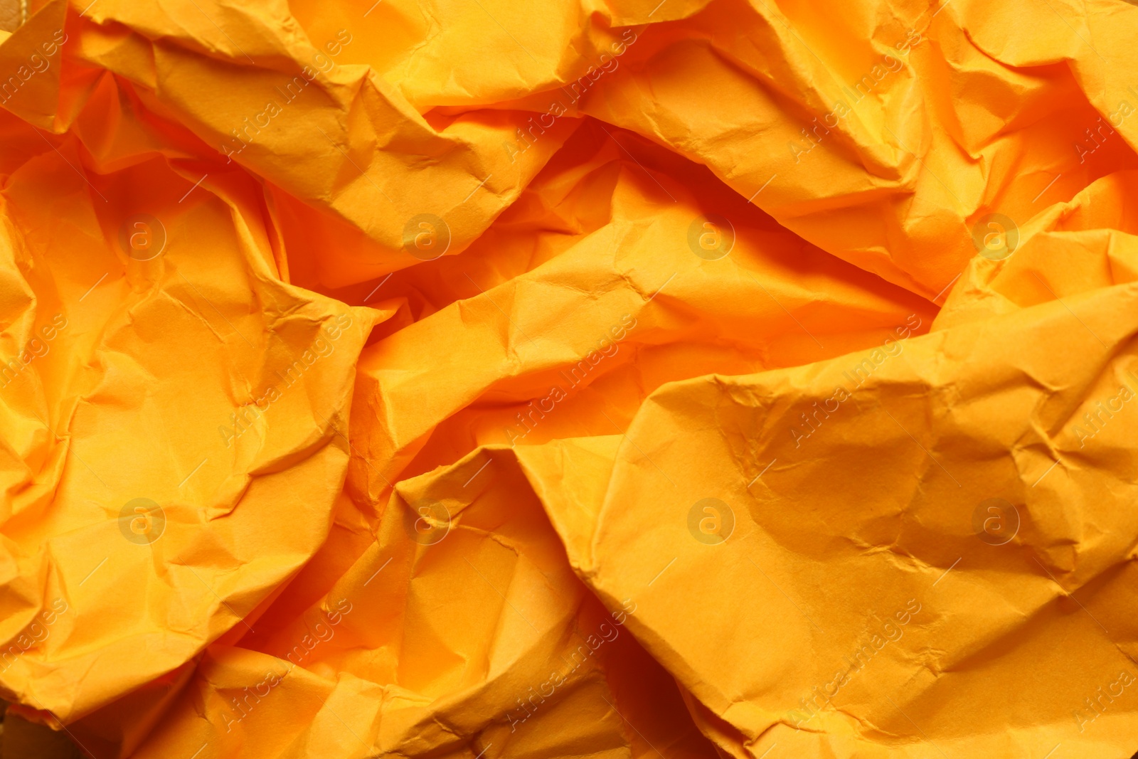 Photo of Texture of orange crumpled paper as background, closeup