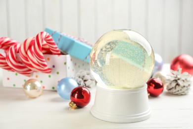 Photo of Beautiful Christmas snow globe and festive decor on white table