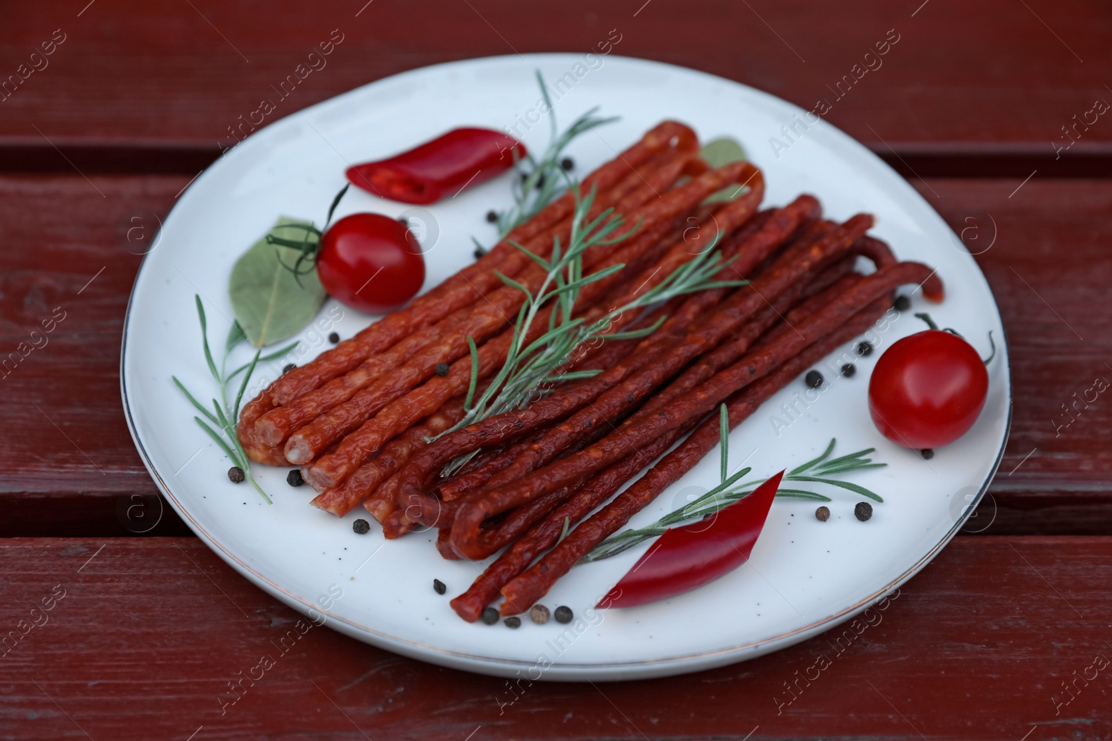 Photo of Tasty dry cured sausages (kabanosy) and ingredients on wooden table