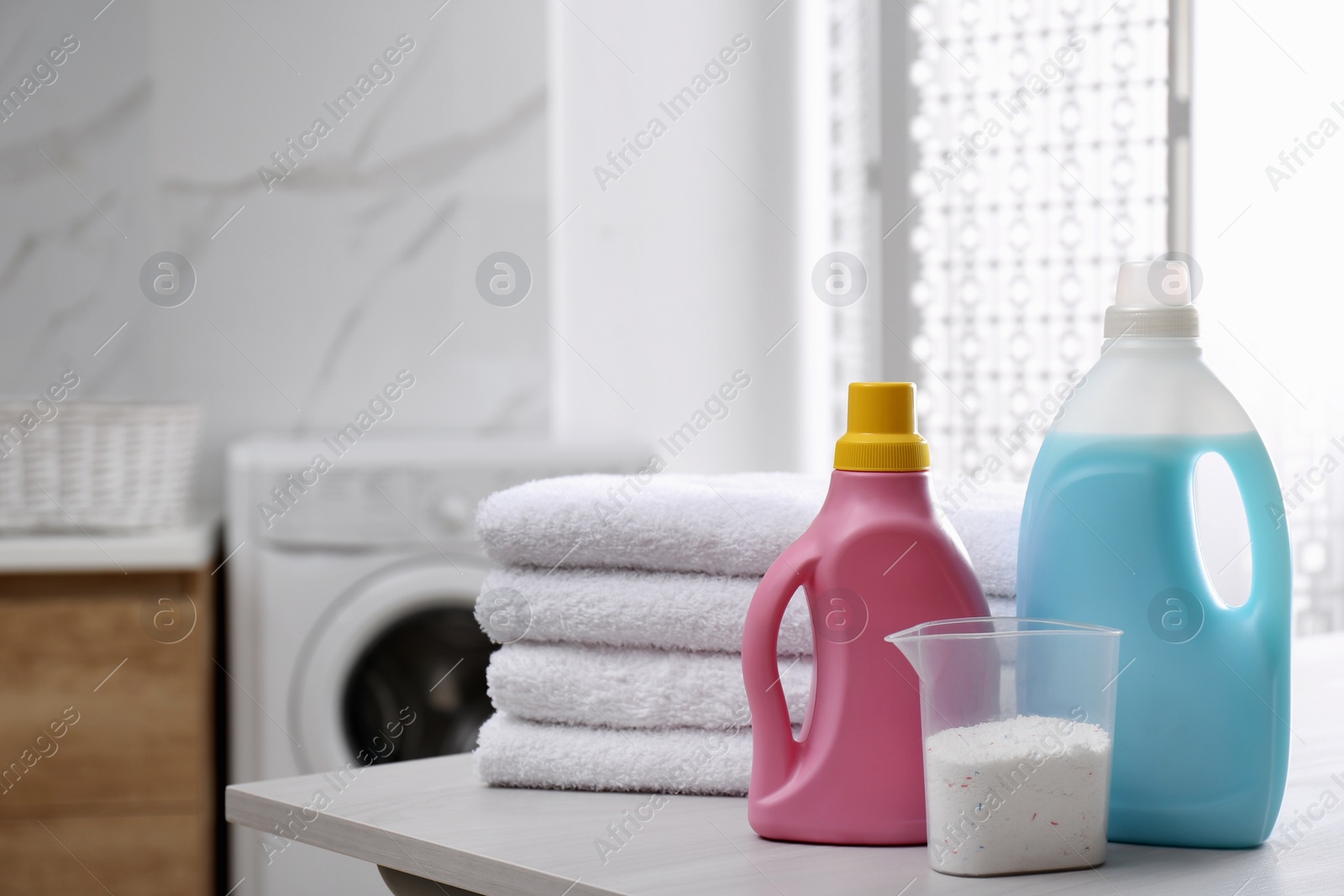 Photo of Stack of folded towels and detergents on white table in bathroom